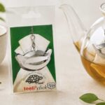 Teeli Click stainless steel tea filter clip attached to glass teapot during tea brewing